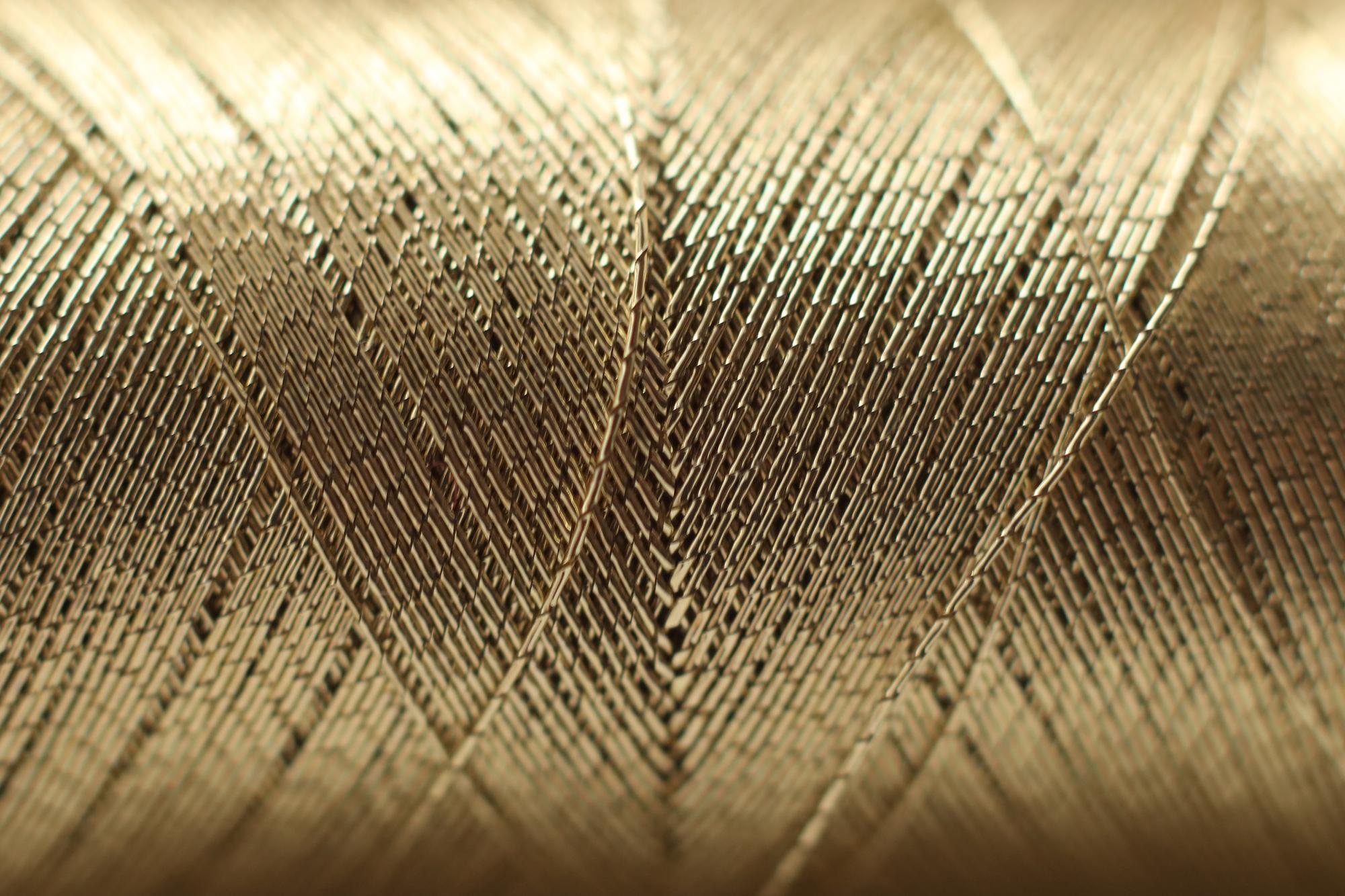 Close-up of embroidered silk panel with gold thread